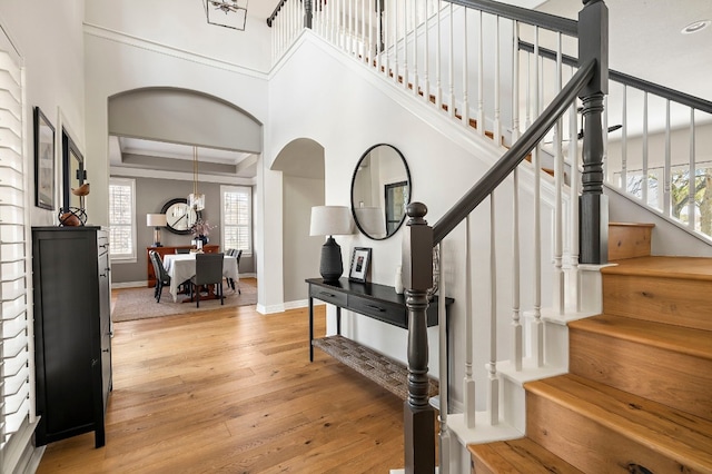 foyer with a raised ceiling, crown molding, and light wood-type flooring