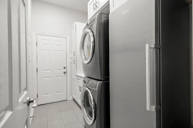 washroom with cabinets, stacked washer and dryer, and light tile patterned flooring