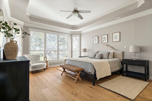 bedroom featuring crown molding, ceiling fan, light wood-type flooring, and a tray ceiling