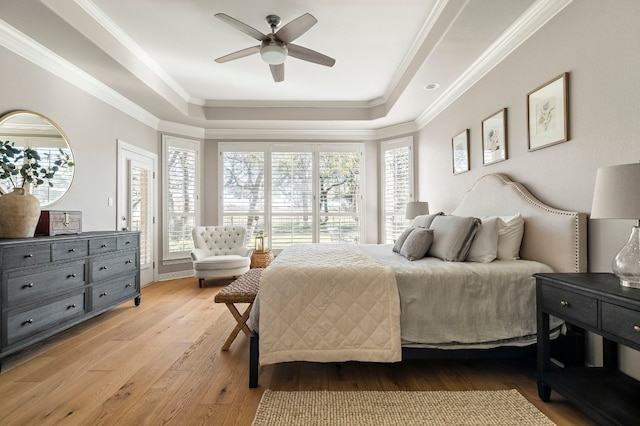 bedroom with ornamental molding, access to outside, light wood-type flooring, and a tray ceiling