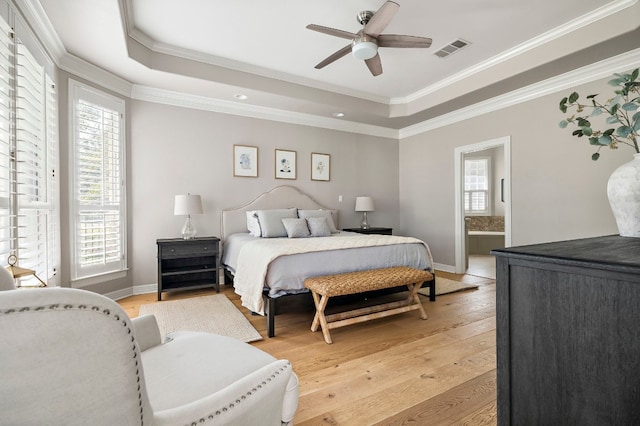 bedroom featuring multiple windows, light hardwood / wood-style floors, and a tray ceiling