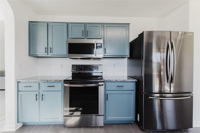 kitchen featuring light stone countertops, appliances with stainless steel finishes, and blue cabinetry