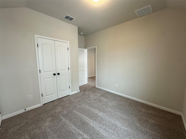 unfurnished bedroom with vaulted ceiling, carpet flooring, visible vents, and a closet