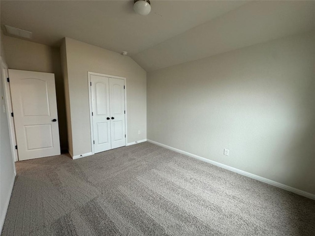 unfurnished bedroom featuring lofted ceiling, a closet, baseboards, and carpet floors