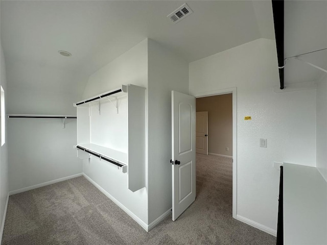 walk in closet with visible vents, light colored carpet, and lofted ceiling