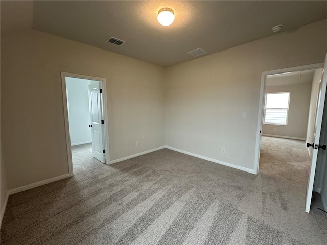 unfurnished room featuring baseboards, visible vents, and carpet floors