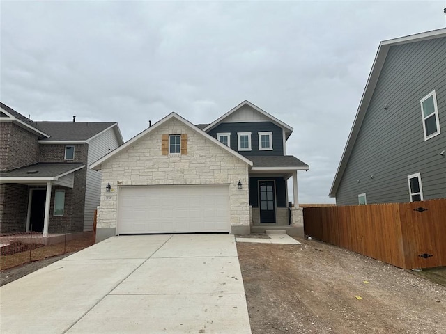 craftsman house with stone siding, driveway, an attached garage, and fence