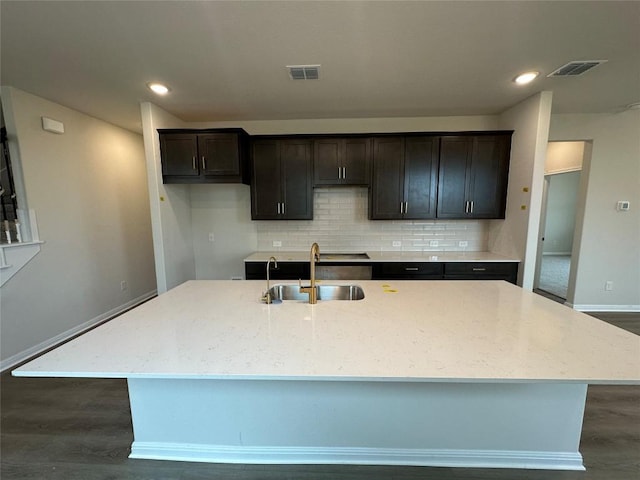 kitchen featuring visible vents, a spacious island, dark wood finished floors, a sink, and tasteful backsplash