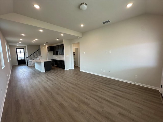 kitchen with visible vents, a kitchen island with sink, dark wood-style flooring, light countertops, and open floor plan