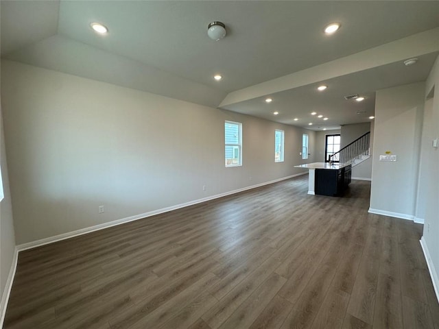 unfurnished living room with dark wood finished floors, stairway, recessed lighting, and baseboards