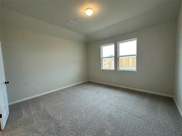 spare room featuring visible vents, lofted ceiling, carpet, and baseboards