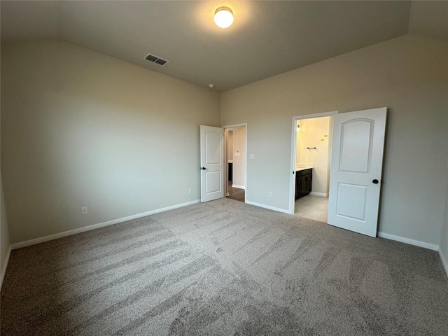 unfurnished bedroom featuring light carpet, visible vents, baseboards, and lofted ceiling