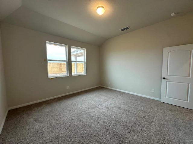 carpeted spare room featuring visible vents, lofted ceiling, and baseboards