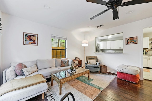 living room featuring dark wood-type flooring and ceiling fan