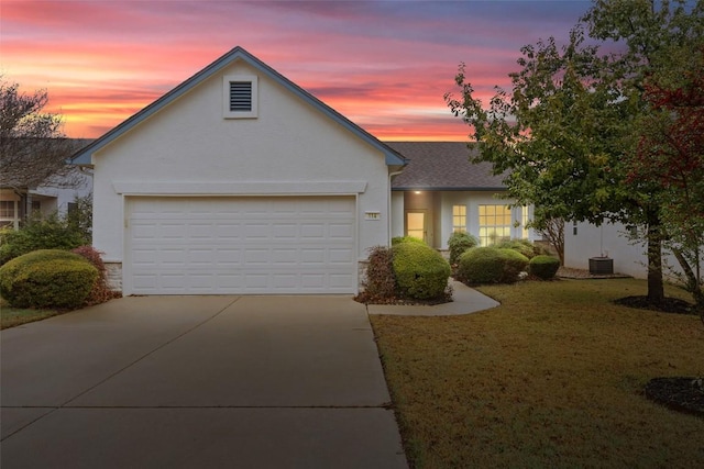 view of front of property with a garage, cooling unit, and a lawn