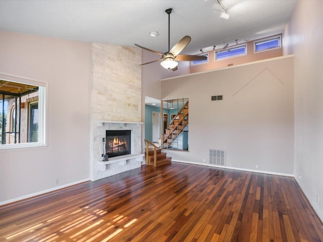 unfurnished living room with ceiling fan, a wealth of natural light, hardwood / wood-style floors, and a fireplace