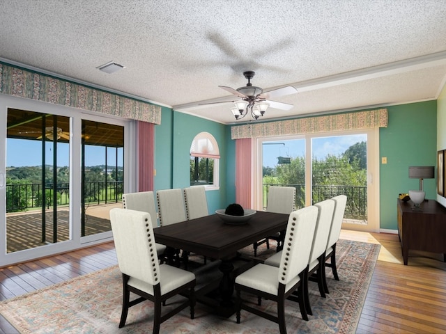 dining space with crown molding, ceiling fan, wood-type flooring, and a textured ceiling