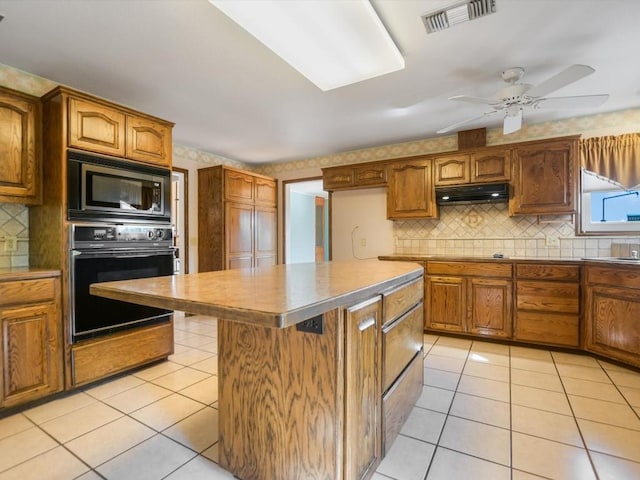 kitchen with built in microwave, black oven, a center island, and light tile patterned flooring