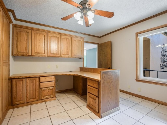 unfurnished office featuring ceiling fan, built in desk, ornamental molding, a textured ceiling, and light tile patterned flooring