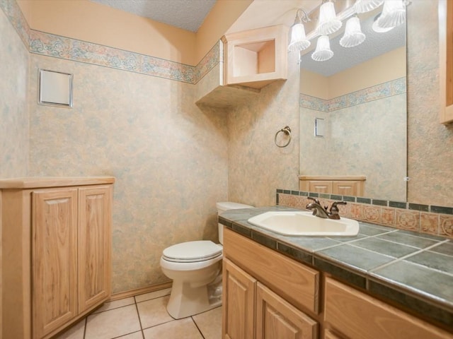 bathroom featuring tile patterned flooring, vanity, a textured ceiling, and toilet