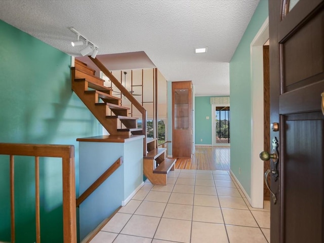 interior space featuring track lighting, a textured ceiling, and light tile patterned floors