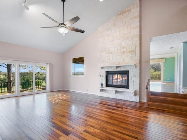 unfurnished living room featuring ceiling fan, high vaulted ceiling, a fireplace, and hardwood / wood-style floors