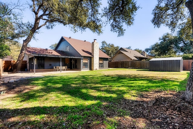 back of house with a patio area, a lawn, and a storage unit