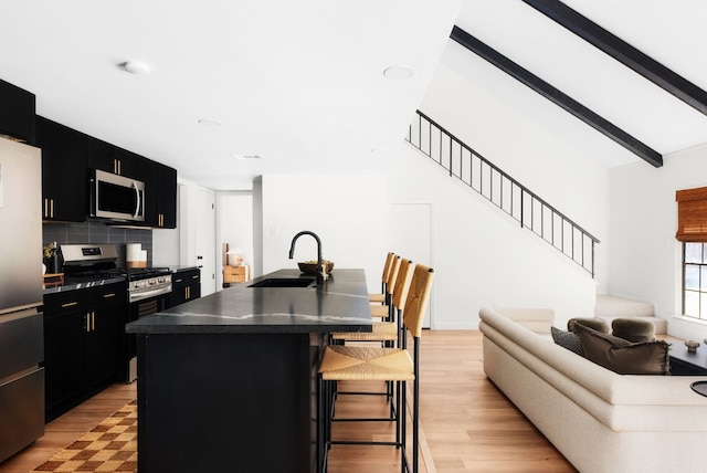 kitchen featuring sink, a kitchen breakfast bar, an island with sink, stainless steel appliances, and backsplash