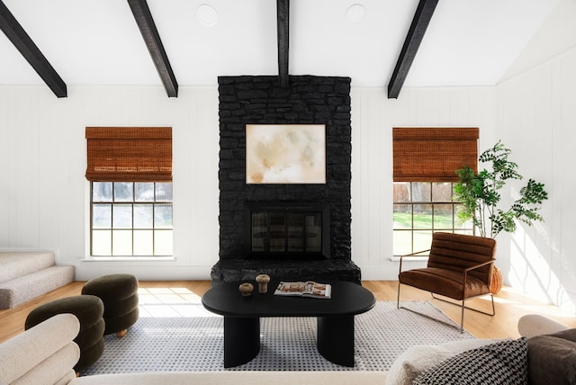 living room featuring lofted ceiling with beams, wood-type flooring, a wealth of natural light, and a fireplace