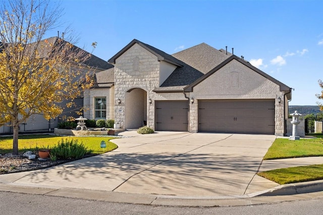 1745 Liguria Ct, Leander, TX 78641 - french country home with stone siding, an attached garage, concrete driveway, and roof with shingles