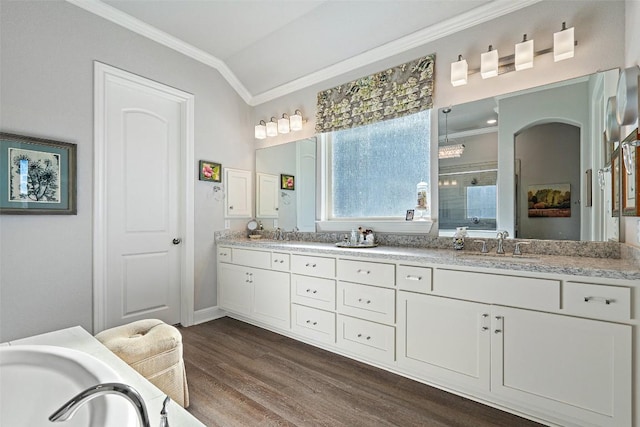 bathroom featuring double vanity, a stall shower, ornamental molding, wood finished floors, and vaulted ceiling