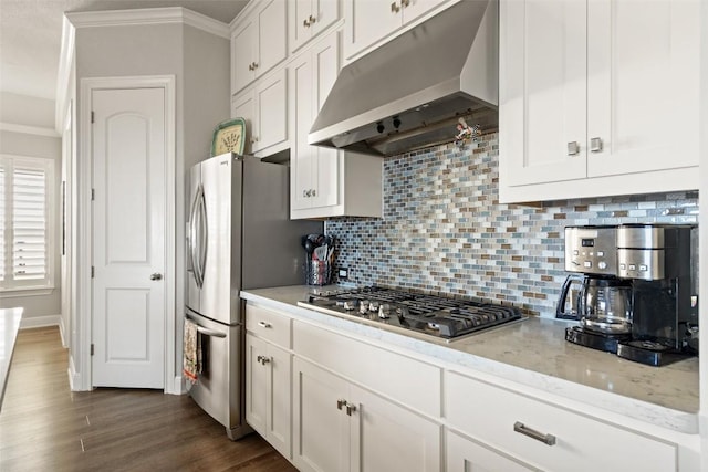 kitchen with light stone counters, white cabinetry, appliances with stainless steel finishes, dark hardwood / wood-style floors, and ornamental molding