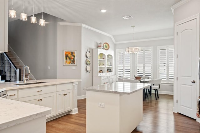 kitchen with sink, white cabinetry, a kitchen island, pendant lighting, and light hardwood / wood-style floors