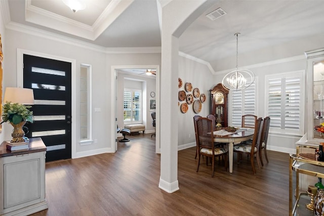 dining room with dark wood-type flooring, crown molding, a raised ceiling, and ceiling fan with notable chandelier