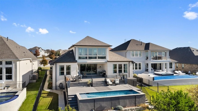 rear view of house featuring a pool with connected hot tub, a lawn, an outdoor hangout area, a residential view, and a fenced backyard