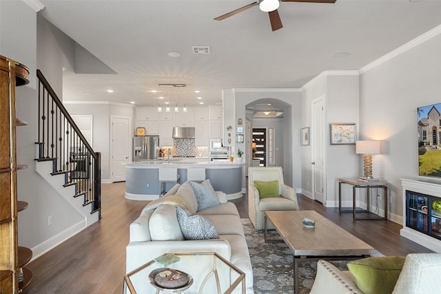 living room with dark wood-type flooring, ceiling fan, and ornamental molding