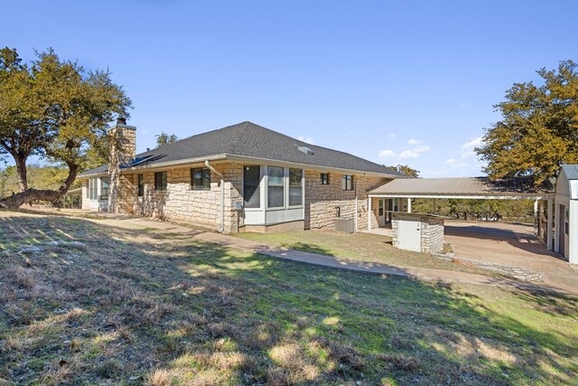 1043 Windmill Rd, Dripping Springs, TX 78620 - rear view of property featuring stone siding, a chimney, a lawn, and a carport