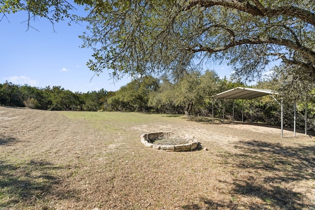 1043 Windmill Rd, Dripping Springs, TX 78620 - view of grassy yard with a carport, dirt driveway, and a forest view