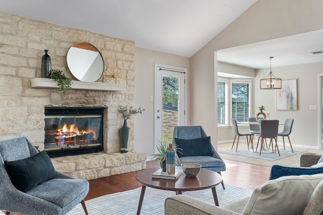 living room with lofted ceiling, a notable chandelier, a fireplace, and light hardwood / wood-style floors