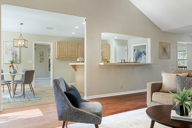 living room featuring lofted ceiling, an inviting chandelier, and light hardwood / wood-style flooring