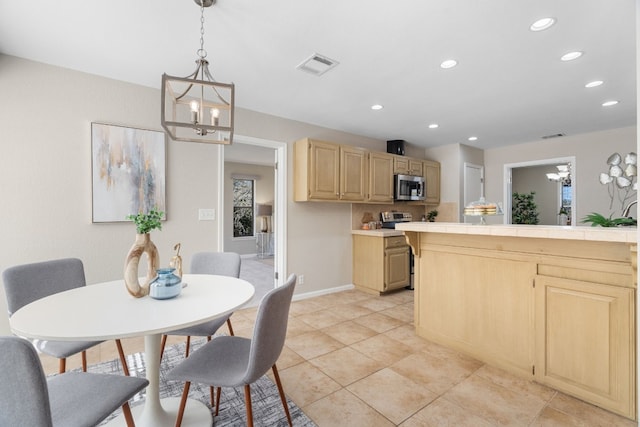 kitchen featuring light tile patterned floors, hanging light fixtures, a notable chandelier, light brown cabinetry, and tile countertops