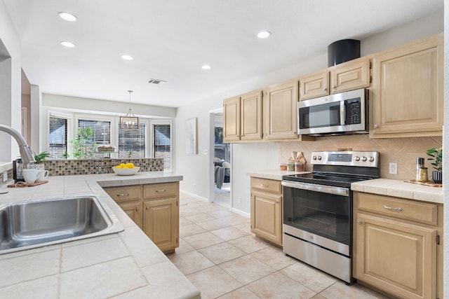 kitchen featuring stainless steel appliances, tile countertops, sink, and backsplash