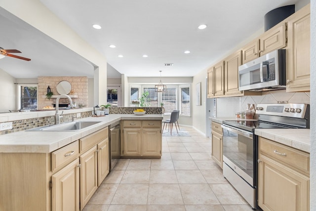 kitchen with sink, stainless steel appliances, tasteful backsplash, tile counters, and light tile patterned flooring