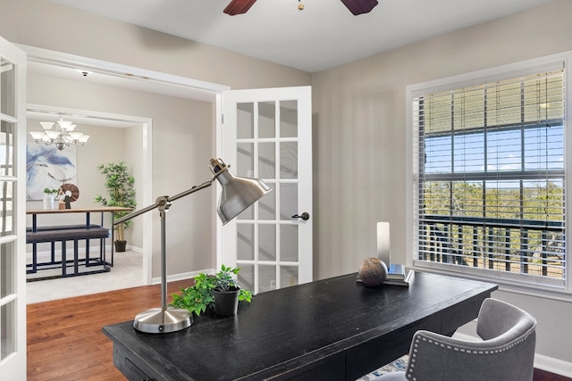 office area with ceiling fan with notable chandelier and wood-type flooring