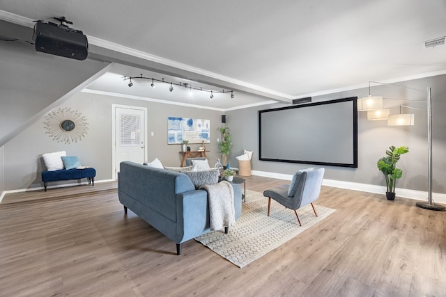 cinema room with ornamental molding, rail lighting, and light hardwood / wood-style flooring