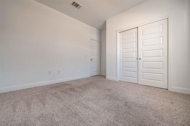 unfurnished bedroom with lofted ceiling, carpet flooring, and a closet