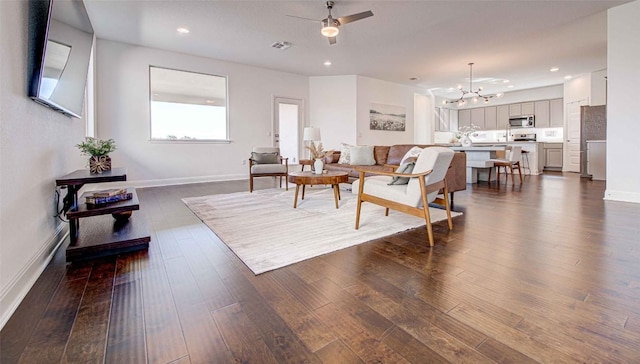 living room featuring dark hardwood / wood-style flooring and ceiling fan with notable chandelier