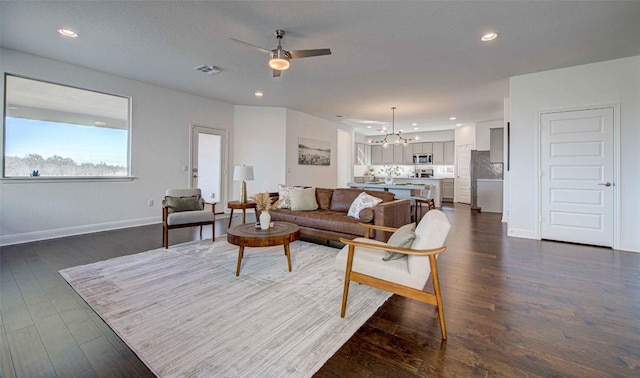 living room with dark hardwood / wood-style flooring, ceiling fan with notable chandelier, and a textured ceiling