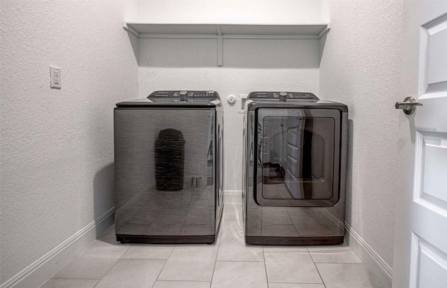 clothes washing area with separate washer and dryer and light tile patterned floors