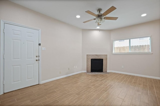 unfurnished living room featuring ceiling fan, a fireplace, and light hardwood / wood-style floors